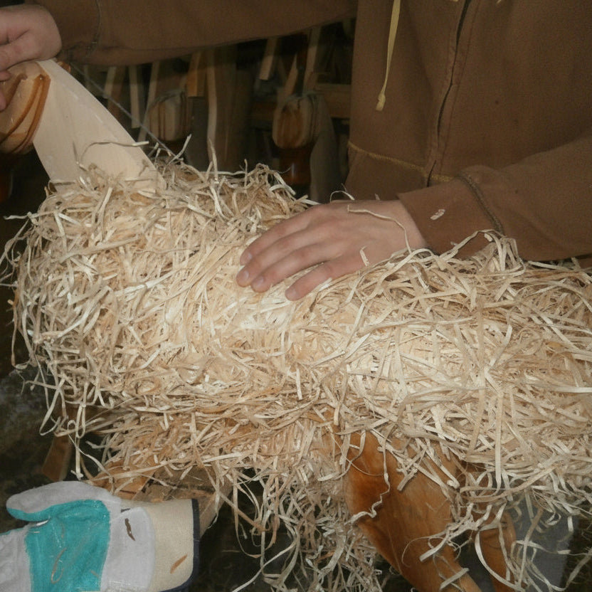 Schaukelpferd wird in der Werkstatt mit Holzwolle umwickelt.